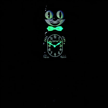 The California Clocks Kit-Cat Klock - Classic Black Gentleman Glow Edition (BC-1 GLOW) features a bow tie and glowing eyes that stand out in the dark. Illumined with a greenish light, its face and details make it easy to read the time—around 9:03—even at night.