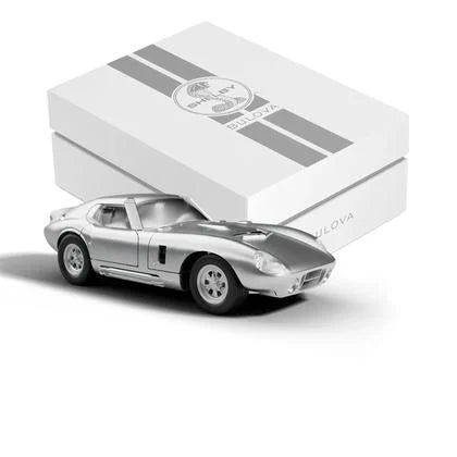 A silver Shelby Racer model car sits before a white, striped Bulova gift box—an ideal showcase for the Limited Edition Bulova Watch - SHELBY® Racer Chronograph - 96K118.