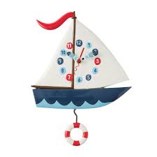 The Enesco Allen Designs Smooth Sailing Clock (6018049) features a sailboat shape with a red flag, circular numbers on the sail, blue boat with wave patterns, and a life preserver pendulum.