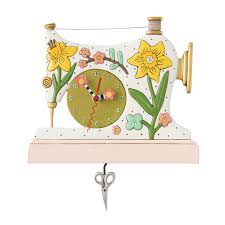 The Enesco Allen Designs Snip And Stitch Clock (6018756) is a sewing machine-shaped decorative clock with yellow and pink flowers and a scissor pendulum.