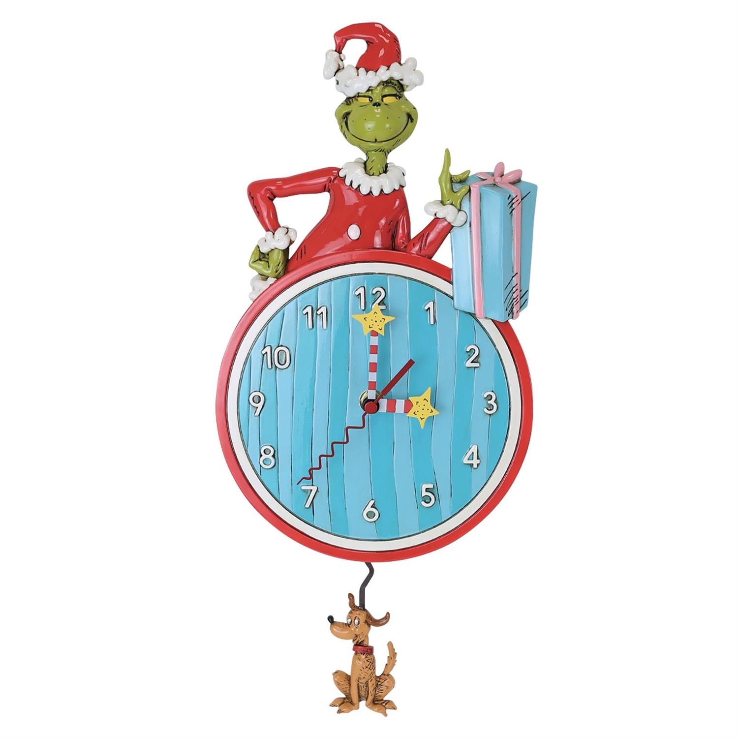 Bring festive cheer to your space with the Enesco Allen Designs Clock - The Grinch Wall Clock (6019434). This whimsical clock features a blue face with a red border and playful numbers. On top, a green character dressed in a red Santa outfit—reminiscent of the Grinch—holds a pink present, while below, a brown dog sporting antlers swings as the pendulum. A fun and unique holiday accent for any room!.