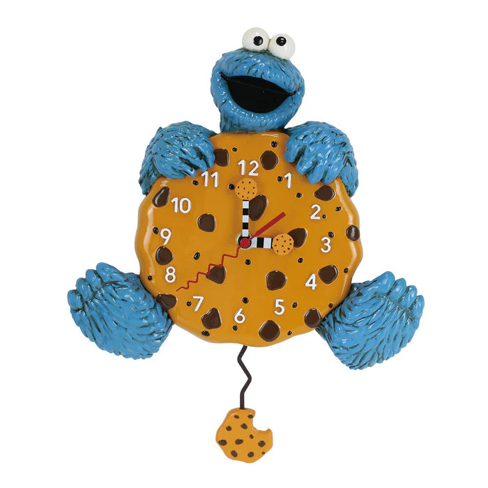 This whimsical Enesco Allen Designs Clock - Cookie Monster Clock (6019559) showcases the beloved Sesame Street character holding a chocolate chip cookie, with the clock face set on the cookie and a swinging, cookie-shaped pendulum hanging beneath.