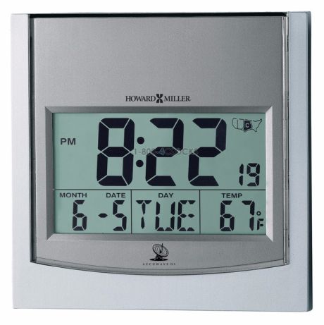 The Howard Miller Clock - Tech Time - 625-235 features a silver frame, large LCD screen displaying 8:22 PM, 6-5 (Tuesday), and 67°F. This atomic radio controlled clock by Howard Miller ensures precise timekeeping.