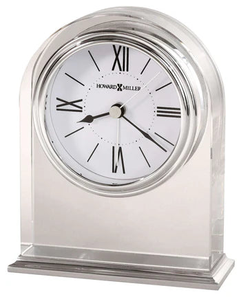 The Howard Miller Clock - Optica (645-757) features a clear acrylic crystal body, white face, black Roman numerals, black hands, and elegant Howard Miller branding on the dial.