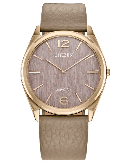 The Citizen Suratto AR3123-00X is a gold-tone Eco-Drive watch with a textured taupe dial, gold hour markers, slim gold hands, numbers 12 and 6 on the face, and a taupe leather strap—no date display for refined simplicity.