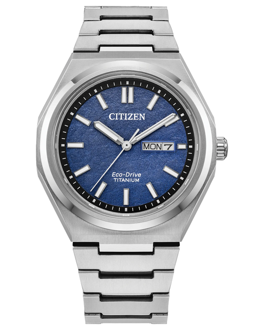 The Citizen Zenshin Super Titanium AW0130-85L features Eco-Drive, a silver band, blue textured dial, white markers and hands, and a day-date display at 3 o’clock.