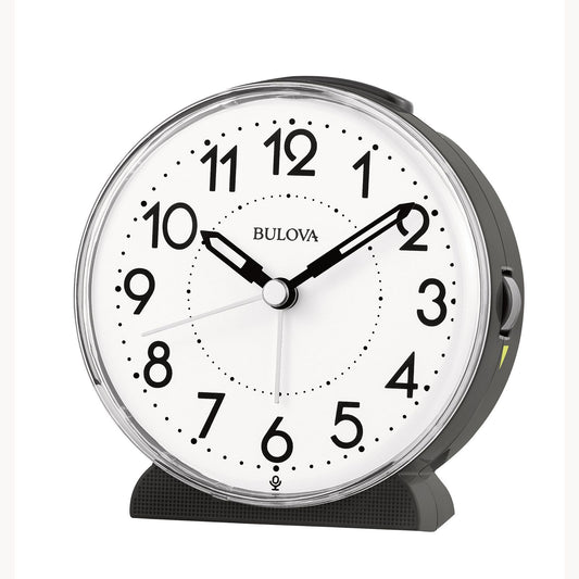 The Bulova Clock - Oracle - B1868 is a round silent quartz alarm clock with a white face, black numbers and hands at 10:10:41, plus a dark gray frame and clear cover—ideal for heavy sleepers seeking reliability.