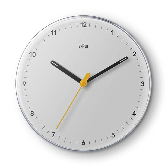 The Ameico Braun BC26W wall clock features a white face, black hour and minute hands, a yellow second hand, silent quartz movement, and simple black tick marks. The time shown is 10:20:33.