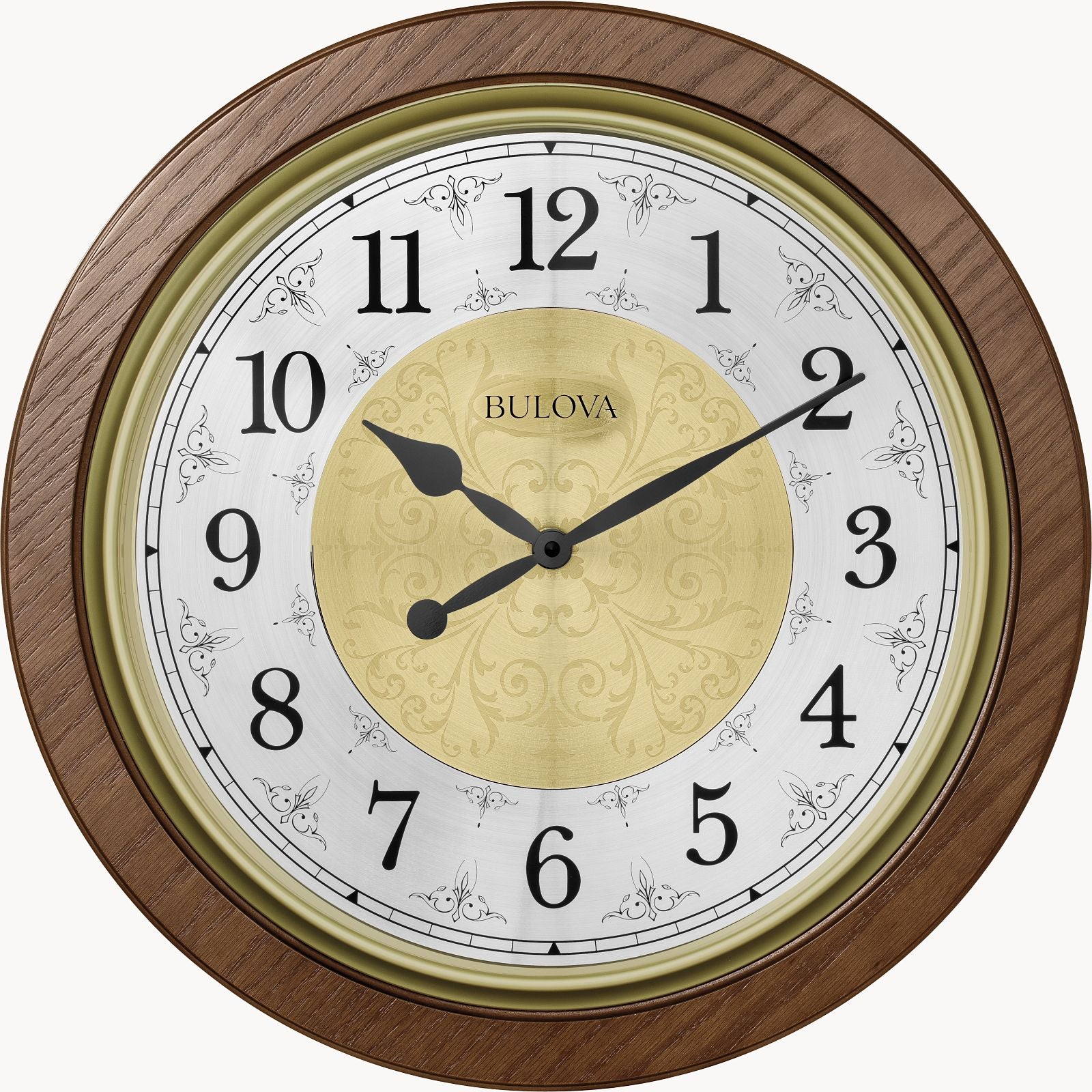The Bulova Clock - Manchester (C4115) features a round brown wood frame, black Arabic numerals and hands, a gold center design, and the Bulova logo. It shows 9:10 and includes Harmonic II PLUS chiming movement.