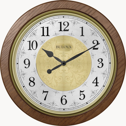 The Bulova Clock - Manchester (C4115) features a round brown wood frame, black Arabic numerals and hands, a gold center design, and the Bulova logo. It shows 9:10 and includes Harmonic II PLUS chiming movement.