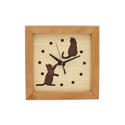 The Sabbath Day Woods Cats At Play Box Clock is a square wooden wall clock with a light face, dark hour dots, black hands, and two cutout cat silhouettes—one sitting top right, one reaching up bottom left. A charming gift for cat lovers.
