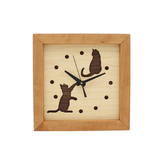The Sabbath Day Woods Cats At Play Box Clock is a square wooden wall clock with a light face, dark hour dots, black hands, and two cutout cat silhouettes—one sitting top right, one reaching up bottom left. A charming gift for cat lovers.