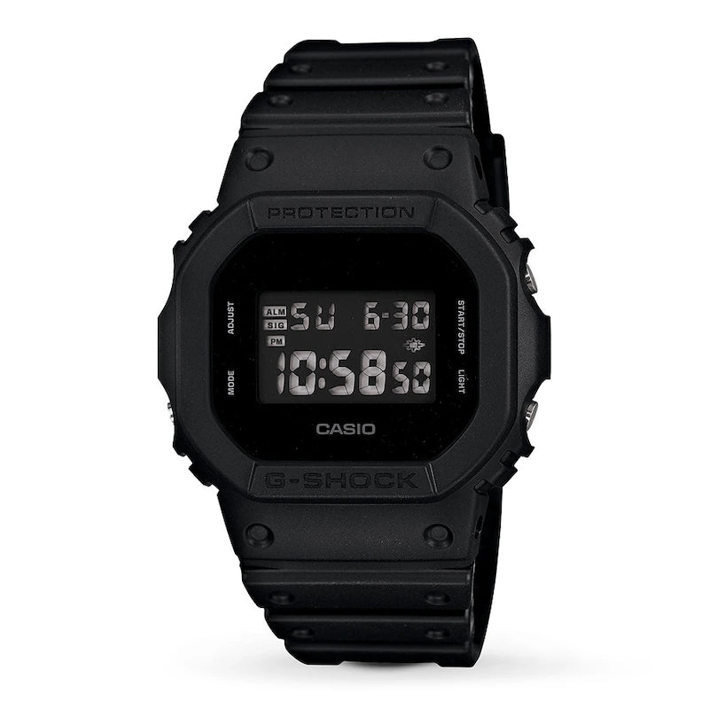 The VLC Distribution Co. G-Shock Watch - Square - DW5600BB-1 is a black digital watch with a durable design and black resin band, displaying 10:58:50, Sunday, and 6-30 on its screen.
