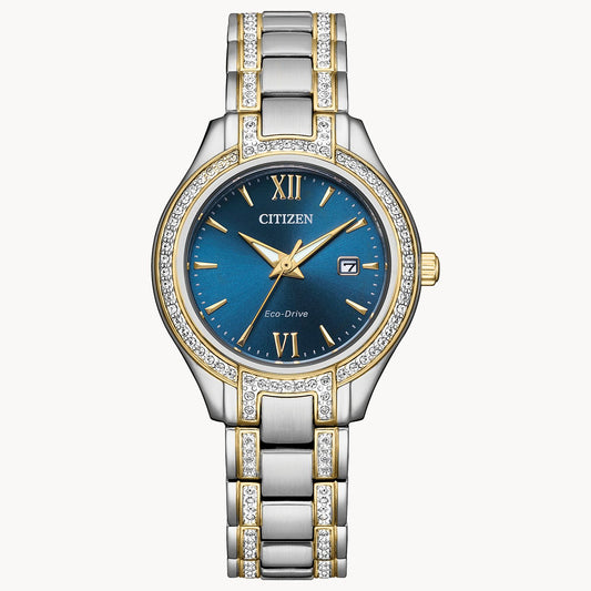 The Citizen Silhouette Crystal (FE1234-50L) women’s watch features a blue dial with Roman numerals, diamond-accented bezel, date window at 3 o’clock, and an elegant two-tone gold and silver stainless steel band.
