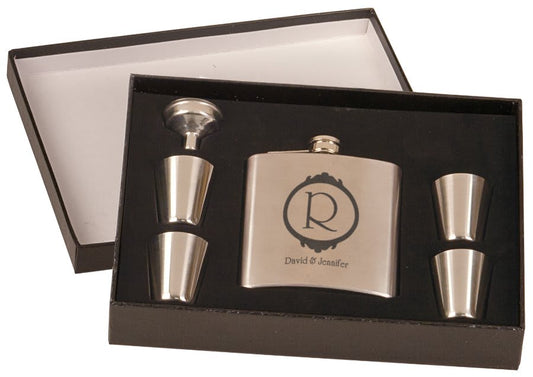 The JDS Flask Set 6 oz (FSK651SET) includes an engraved stainless steel flask, four metal shot glasses, and a funnel in a black foam insert—an elegant gift set in a stylish presentation box.