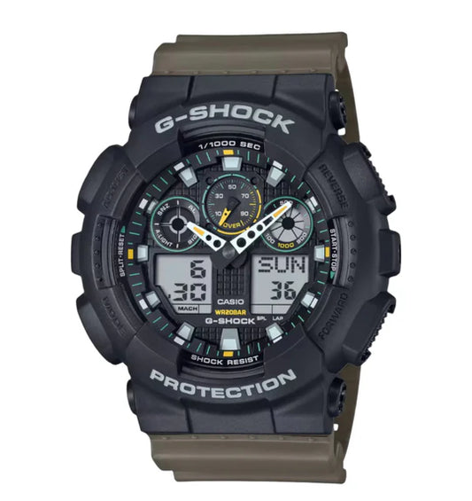 The Casio G-Shock Watch - GA-100TU-1A3 by VLC Distribution Co. features a rugged black, shock-resistant design with "Protection" and "G-Shock" on the bezel, multi-dial display, and green/yellow accent hands for time and date.