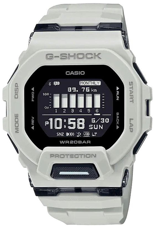 The G-Shock Watch - GBD200UU-9 by VLC Distribution Co. features a black and white display showing 10:58, June 30, and daily stats. Labeled buttons encircle the face of this stylish white sports tech digital wristwatch.