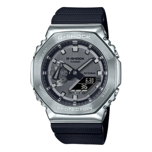 The VLC Distribution Co. G-Shock Watch - Metal Bezel - GM2100-1A features a round metal bezel, black strap, analog and digital displays, labeled adjust/mode/light/start buttons, and a face with both hands and digital screens.