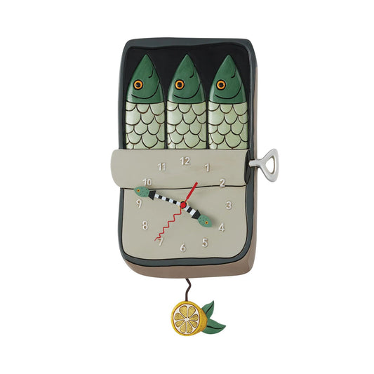 The Enesco Allen Designs Feeling Salty Clock (6017321) is a whimsical wall clock shaped like a sardine tin, featuring three fish on top, a winding key on the side, a fish-shaped hand, and a lemon slice pendulum.