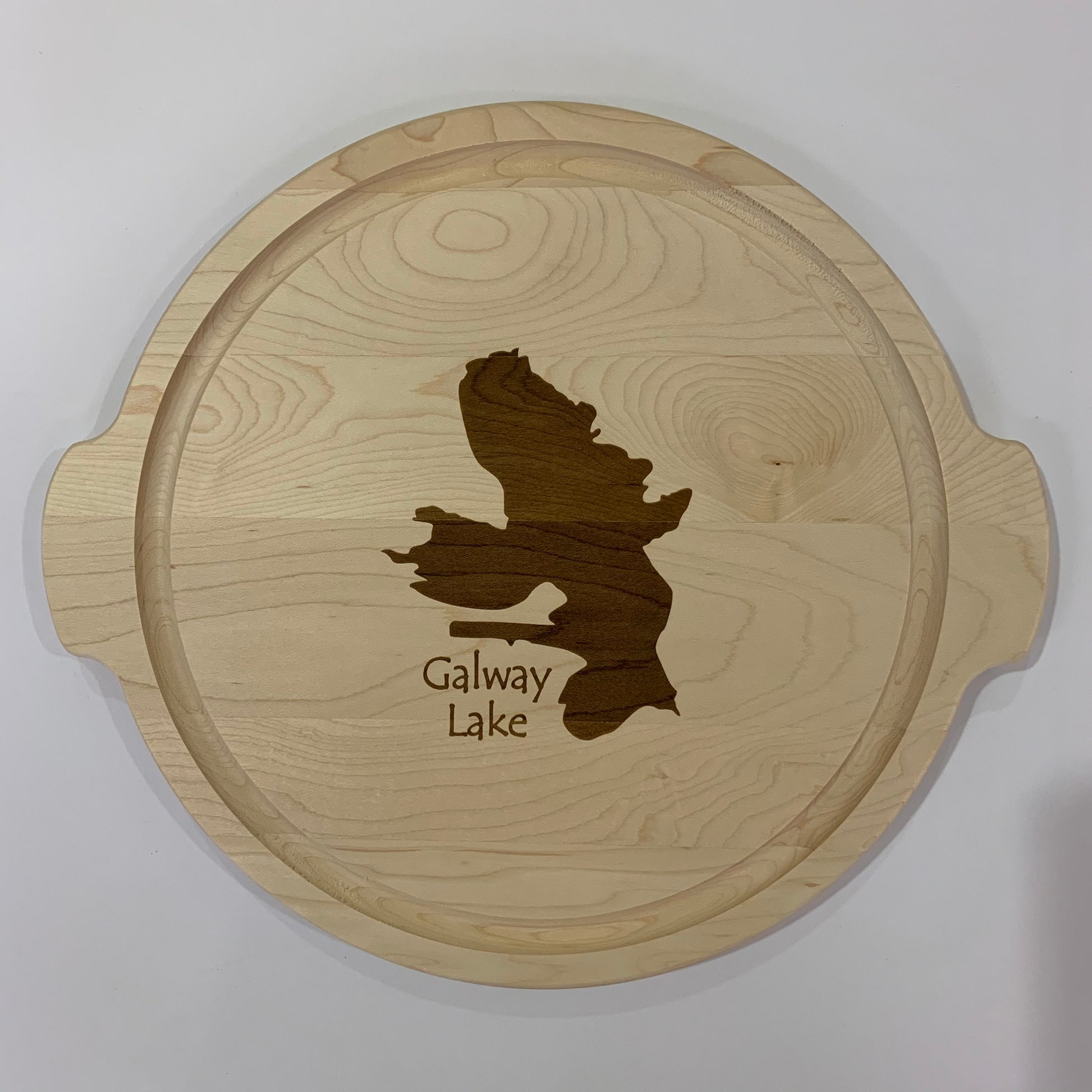 The TS Cutting Board by Time Square Clock Shop is a round custom lake cutting board featuring a laser-engraved Galway Lake design with side handles and "Galway Lake" text, perfect for any home.