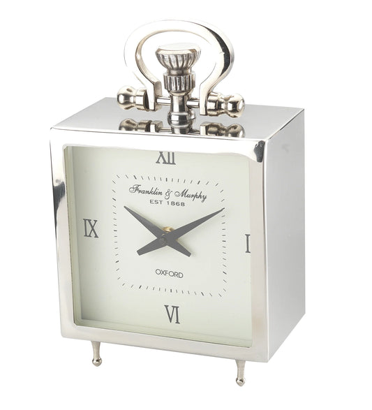 The A Sanoma Steel/Aluminum Small Tabletop Clock (KG502) features a silver rectangular design, white face, black Roman numerals and hands, a decorative handle, small legs, and Franklin & Murphy EST 1868 OXFORD labeling.