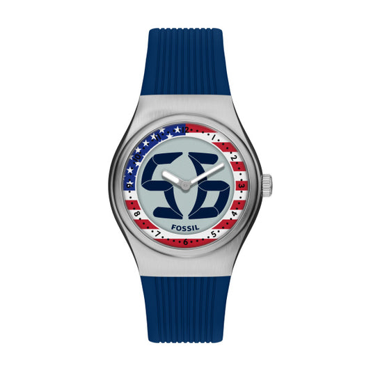 The Fossil Watch - Limited Edition Big Tic (LE1235) by Fossil showcases a blue strap, silver case, double G logo dial, and a red, white, and blue star bezel. "FOSSIL" appears at the bottom of this unique archival design.