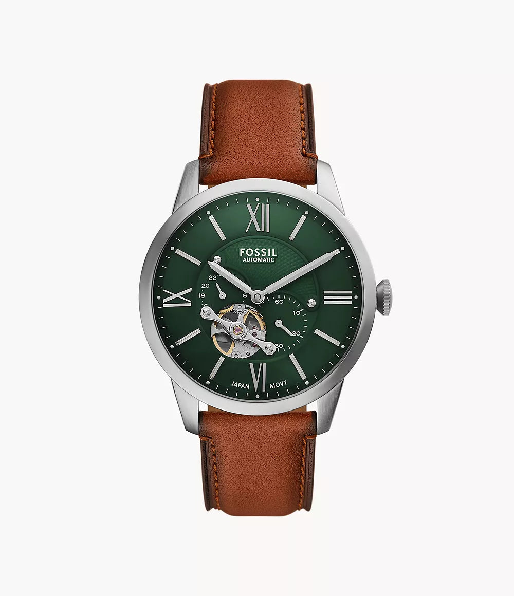 The Fossil Townsman Automatic ME3265 features a green open heart dial with silver Roman numerals, exposed gears, a brown leather strap, and a metallic silver case with the Fossil logo below 12 o’clock.