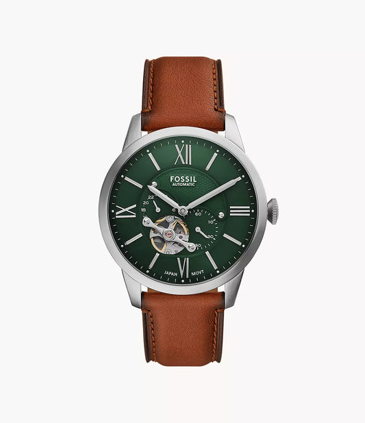 The Fossil Townsman Automatic ME3265 features a green open heart dial with silver Roman numerals, exposed gears, a brown leather strap, and a metallic silver case with the Fossil logo below 12 o’clock.