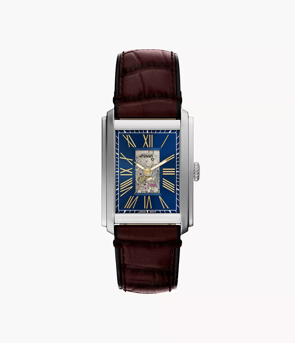 The Fossil Watch - Carraway Automatic - ME3273 by Fossil features a brown leather strap, blue skeleton dial with gold Roman numerals, visible gears, and a silver case, shown from above on a white background.