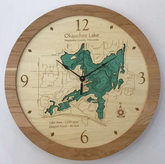 The Lake Art Lake Clock - Okauchee Lake features a wooden frame, an engraved map with depth contours of Okauchee Lake in Waukesha County, Wisconsin, and displays the time as 5:00.