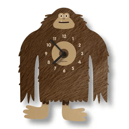 The Popclox Clock - Bigfoot Pendulum Clock (PCPEN061) by Popclox features a friendly, cartoon-style brown Bigfoot with long arms, wide feet, a smiling face, and a belly clock with white numbers and black hands.
