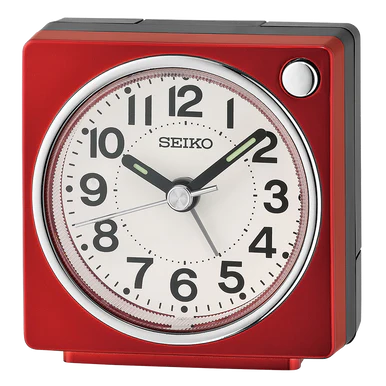 A Seiko Clocks - QHE196RLH alarm clock in red, featuring a round analog face with black numerals and hands, displays the time as 1:51:40. The clock is set within a square frame and has a silver button on the top right.