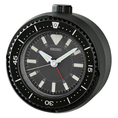 The Seiko Clocks - Heritage Design - QHE207KLH is a black alarm clock styled like a diving watch, with bold white hour markers, large hands, a red-tipped quiet sweep second hand, and a rotating bezel with minute markings.