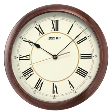 A round Seiko Clocks - Wall Clock - QXA598ALH features a brown wooden grain finish frame, Roman numerals, and three hands displaying the time as 10:09:36. The Seiko brand name is printed at the top center of the clock face, and its precise quartz movement ensures dependable accuracy.