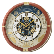 The Seiko Clock - Castle Night Melodies In Motion (QXM378BRH) features a red and gold frame, ornate gold and blue details, castle artwork, and a white face with black numbers and gold hands—a striking musical wall clock for any room.