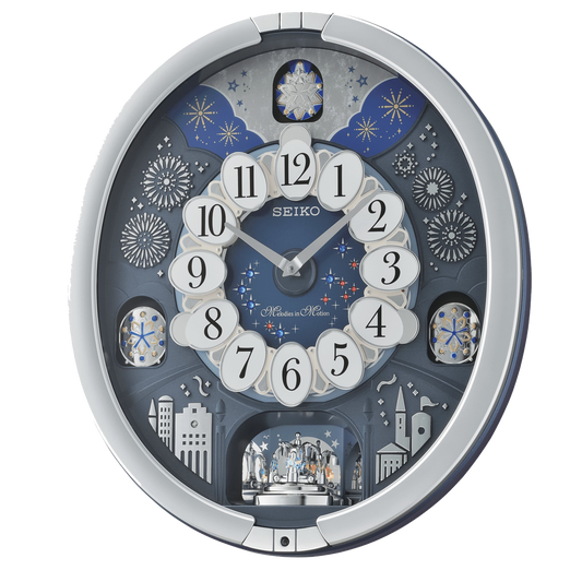The Seiko Starry Night Melodies in Motion Clock (QXM379SRH) features an ornate cityscape with fireworks, stars, white oval number panels, and a decorative rotating scene adorned with sparkling Swarovski crystals.