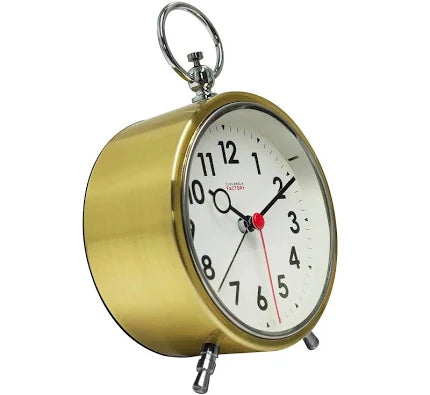 The Cloudnola Factory Gold Alarm Clock (SKU0119) features a vintage minimalist design with a white face, black numbers, and three hands. Sitting on two legs with a ring handle, it’s the perfect charming desk clock from Cloudnola.