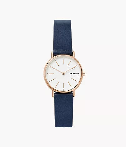 The Fossil Skagen Watch - Signatur Lille (SKW2838) showcases Scandinavian minimalism with a white round face, gold details, slim blue leather strap, and a gold case for an elegant look.