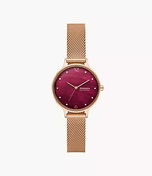 The Skagen Watch - Anita Lille - SKW3150 by Fossil features a gold mesh band, round maroon face, gold markers and hands, and the SKAGEN Denmark name—a blend of elegance and modern style.