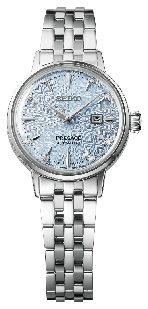 The Seiko Presage SRE007 by Seiko is a Japanese mechanical watch featuring a silver metal band, textured light blue dial, silver hour markers, date display at 3 oclock, and Made in Japan on the dial.