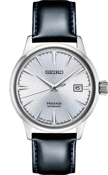 The Seiko Presage Automatic SRPB43 features a silver sunburst dial, date at 3 o’clock, silver markers, stainless steel case, and black leather strap with blue stitching.