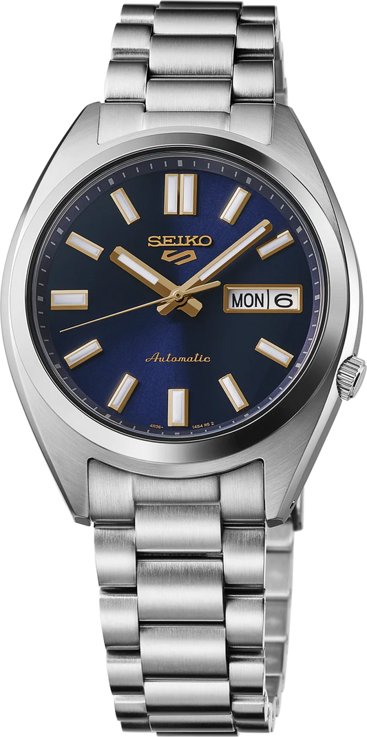 The Seiko 5 Sport SRPL55 automatic watch features a stainless steel band, dark blue dial, gold markers and hands, plus a day-date display (MON 6) at the 3 o'clock position.