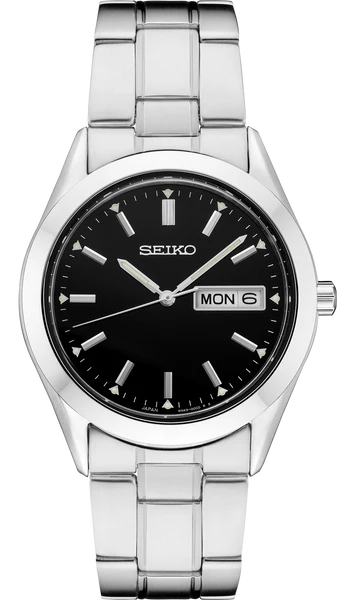 The Seiko Essentials Collection SUR361 watch features a stainless steel case, black dial, silver hour markers and hands, a date-day window at 3 o’clock showing MON 6, and a polished metal link band for a classic look.