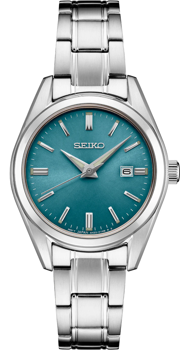 The Seiko Watch - Essentials - SUR531 features a stainless steel case, blue dial, silver hour markers and hands, a date window at 3 o'clock, and a brushed metal bracelet.