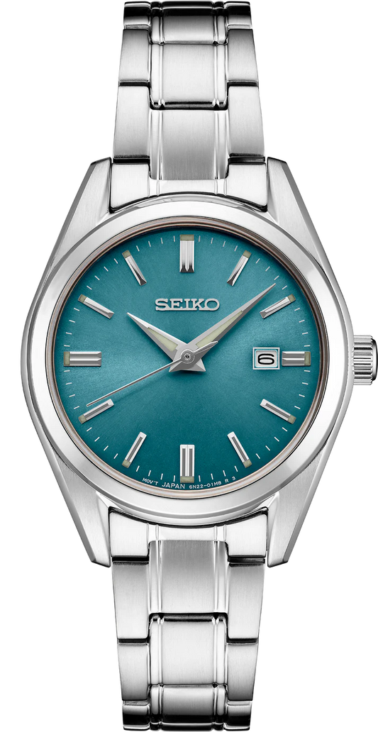 The Seiko Watch - Essentials - SUR531 features a stainless steel case, blue dial, silver hour markers and hands, a date window at 3 o'clock, and a brushed metal bracelet.