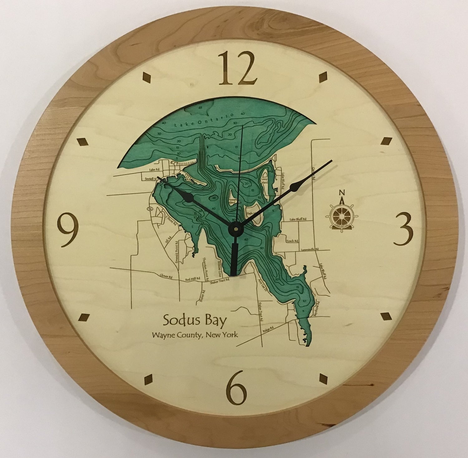 The Lake Art Lake Clock - Sodus Bay is a custom wooden wall clock featuring a map of Sodus Bay, NY with green and black water depth contours and standard black hour, minute, and second hands.