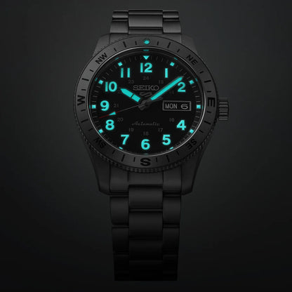The Seiko 5 Field Series HDB008 wristwatch by Seiko features a durable black metal band and displays luminous blue hour markers and hands for visibility in the dark. This robust automatic field watch also includes a day and date window positioned on the right side of the dial.