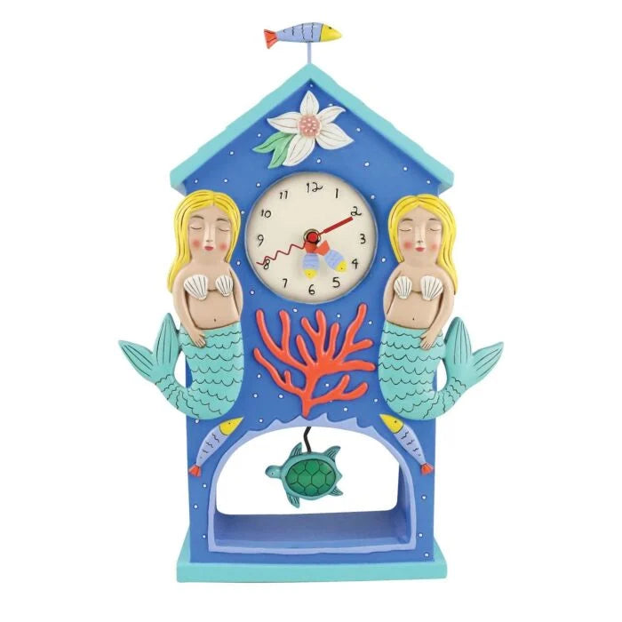 The Enesco Allen Designs Clock - Beach Time Mantel Clock (6012492) is a blue beach-themed mantel clock with two blonde mermaids, red coral, fish, a flower, and a green turtle pendulum in a house-shaped frame.