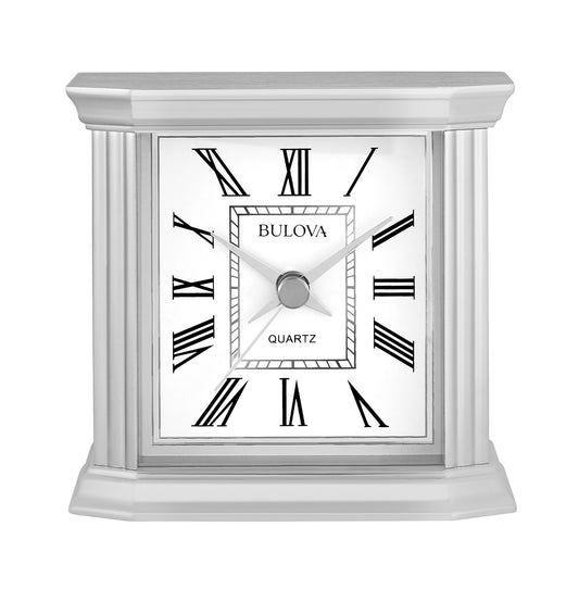 The Bulova Wilton B1714 is a square clock with a polished silver finish, white face, black Roman numerals, silver hands, and classic styling featuring decorative side columns.
