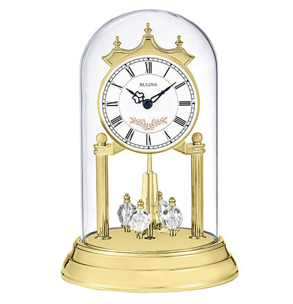 A gold-toned Bulova Clock - Heather - B8821 mantel clock with a white face and Roman numerals, encased in a glass dome with a rotating crystalline pendulum.